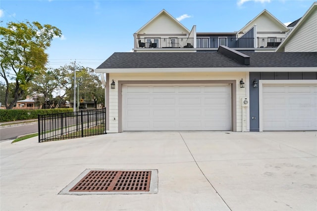 view of front of property featuring board and batten siding, concrete driveway, roof with shingles, and a balcony