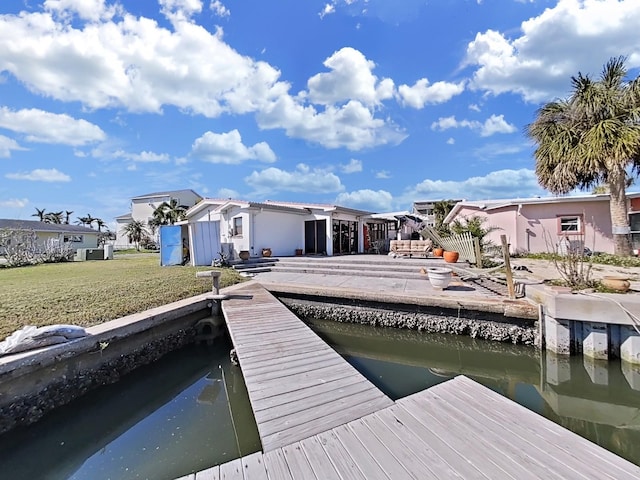 view of dock with a water view and a lawn