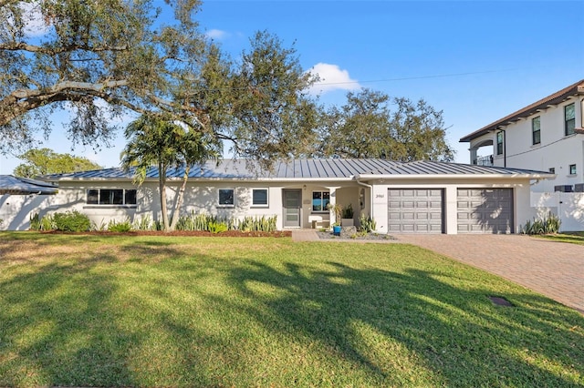 single story home featuring a garage, a standing seam roof, and a front lawn