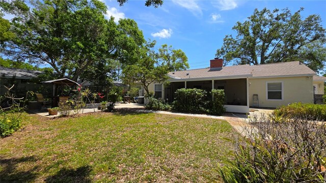 1372 Palmetto St, Clearwater, FL 33755 - rear view of property featuring a chimney, a sunroom, a patio area, and a yard