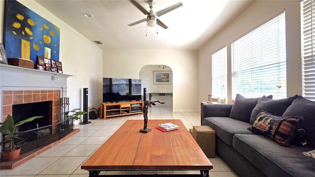 1372 Palmetto St, Clearwater, FL 33755 - living room with visible vents, ceiling fan, a tiled fireplace, arched walkways, and light tile patterned floors