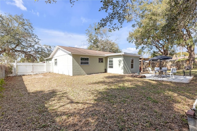 back of house with a patio and a lawn