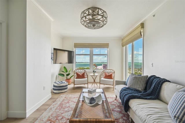 living area with baseboards, light wood-style floors, and crown molding