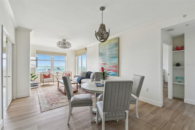 dining area featuring a textured ceiling, light wood-type flooring, baseboards, and crown molding