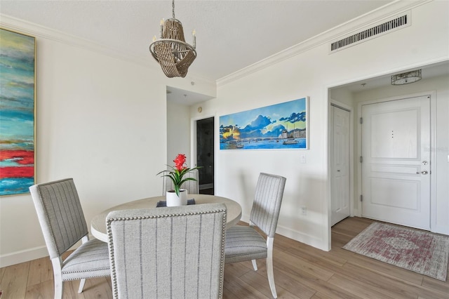 dining space with baseboards, wood finished floors, visible vents, and crown molding