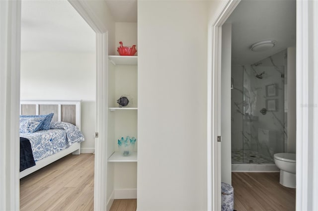 bedroom with connected bathroom, baseboards, and wood finished floors