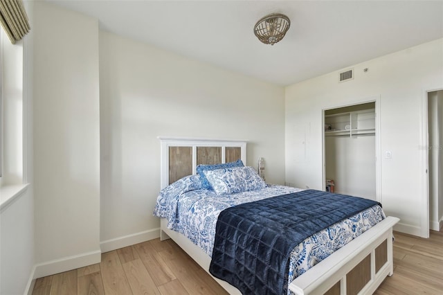 bedroom with light wood-type flooring, a closet, visible vents, and baseboards