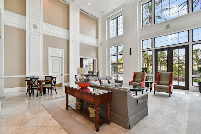 living area featuring french doors, light tile patterned flooring, a towering ceiling, and baseboards