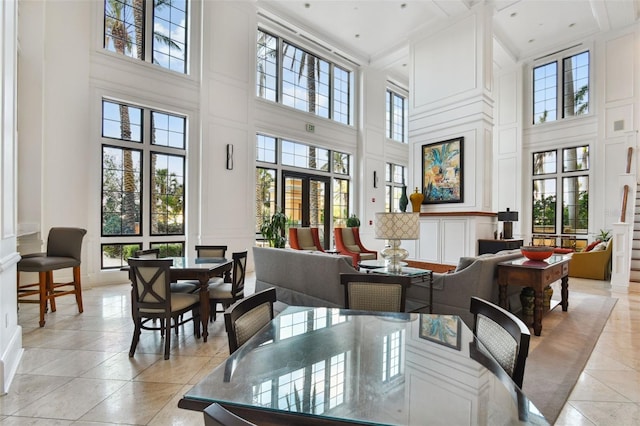 dining space with plenty of natural light, light tile patterned flooring, a decorative wall, and a towering ceiling