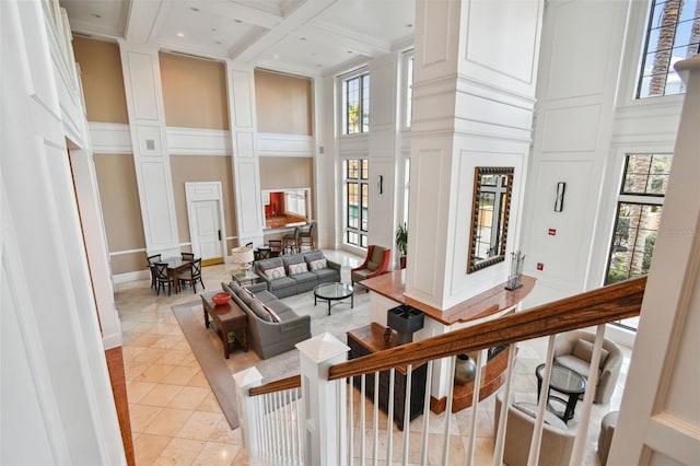 interior space with coffered ceiling, a towering ceiling, and a decorative wall