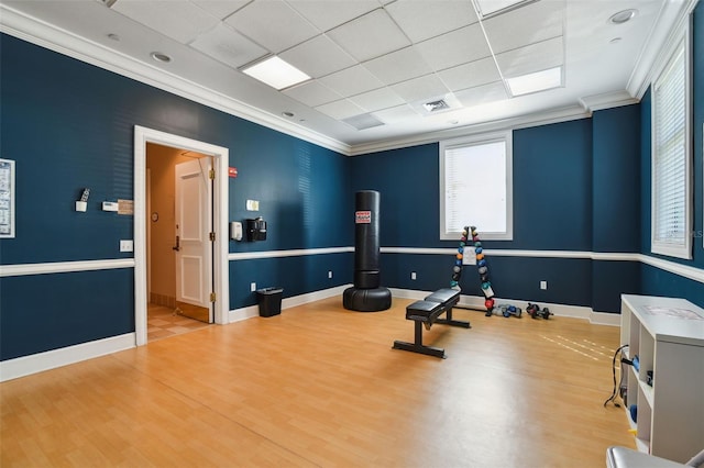 exercise area with ornamental molding, visible vents, baseboards, and wood finished floors