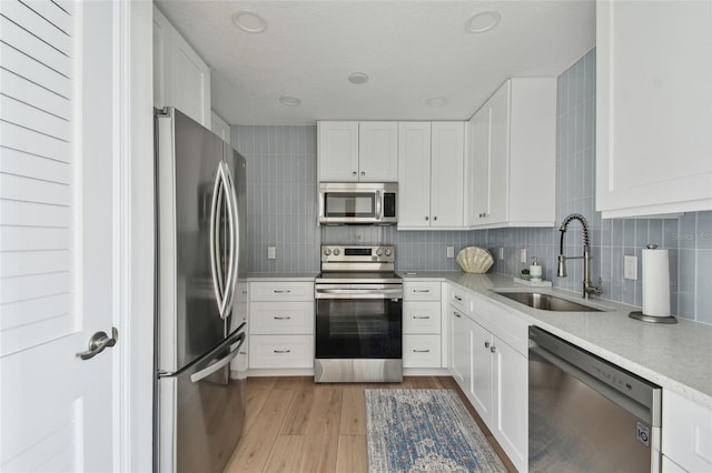 kitchen featuring stainless steel appliances, backsplash, a sink, and light countertops