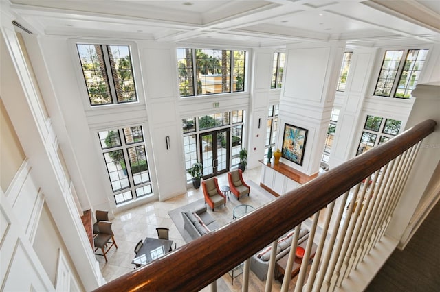 interior space featuring a wealth of natural light, french doors, coffered ceiling, and a towering ceiling