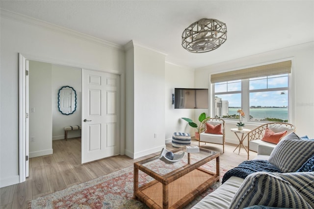 living room with crown molding, a water view, baseboards, and light wood-style floors