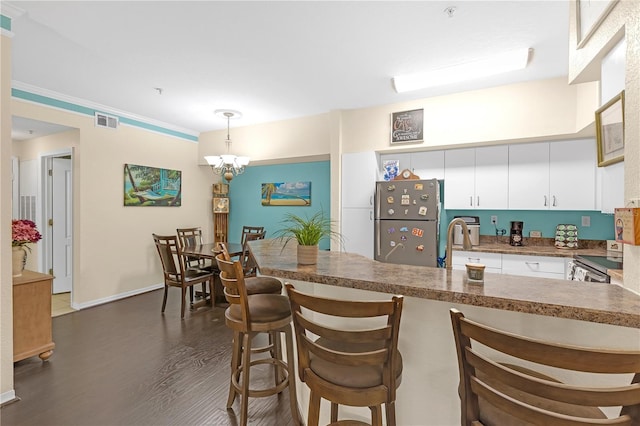 kitchen with white cabinetry, dark hardwood / wood-style floors, kitchen peninsula, pendant lighting, and stainless steel appliances