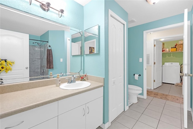 bathroom featuring tiled shower, vanity, washer / clothes dryer, tile patterned floors, and toilet