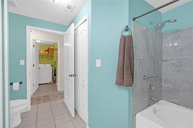 bathroom featuring tiled shower / bath, tile patterned floors, toilet, and washer / dryer