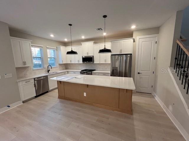 kitchen with stainless steel appliances, a kitchen island, and white cabinets