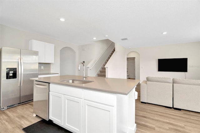 kitchen featuring sink, white cabinets, a kitchen island with sink, stainless steel appliances, and light wood-type flooring