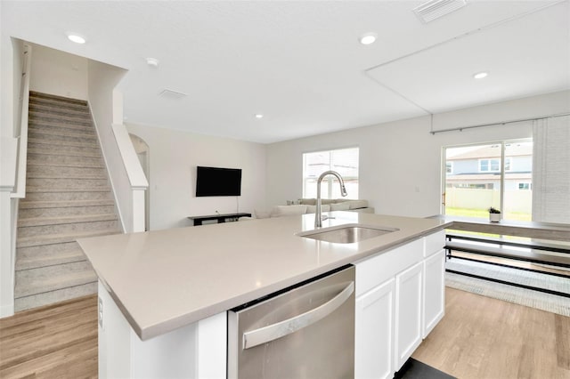 kitchen with sink, white cabinets, stainless steel dishwasher, plenty of natural light, and a center island with sink