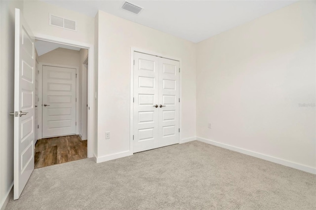 unfurnished bedroom with light colored carpet and a closet