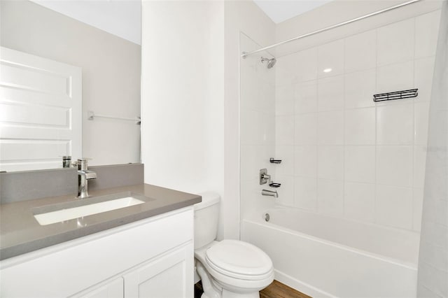 full bathroom featuring tiled shower / bath, vanity, and toilet