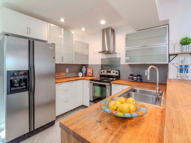 kitchen with sink, white cabinets, wooden counters, stainless steel appliances, and wall chimney range hood