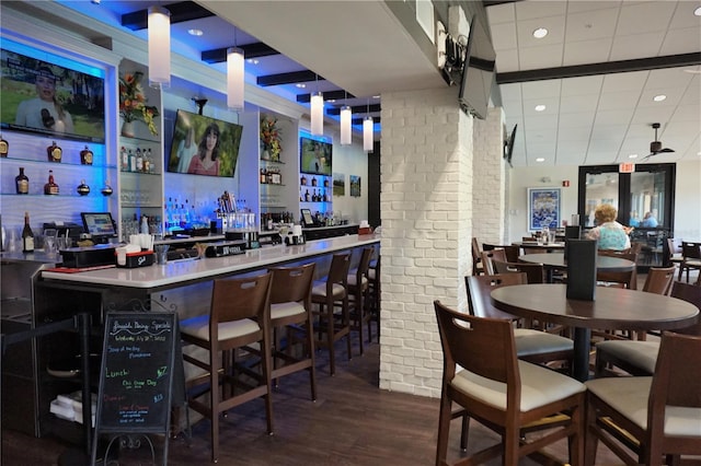 bar featuring hanging light fixtures, wood-type flooring, and brick wall