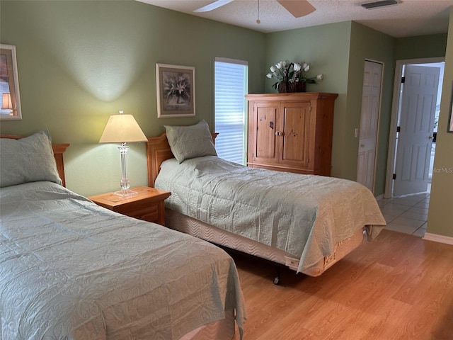 bedroom featuring ceiling fan, light hardwood / wood-style flooring, and a textured ceiling