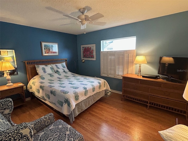 bedroom with hardwood / wood-style flooring, ceiling fan, and a textured ceiling