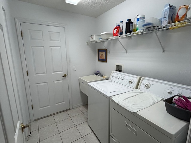 laundry room with separate washer and dryer, light tile patterned floors, and a textured ceiling