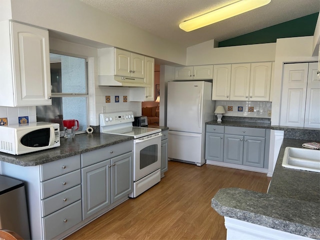 kitchen featuring gray cabinets, lofted ceiling, white cabinets, light hardwood / wood-style floors, and white appliances