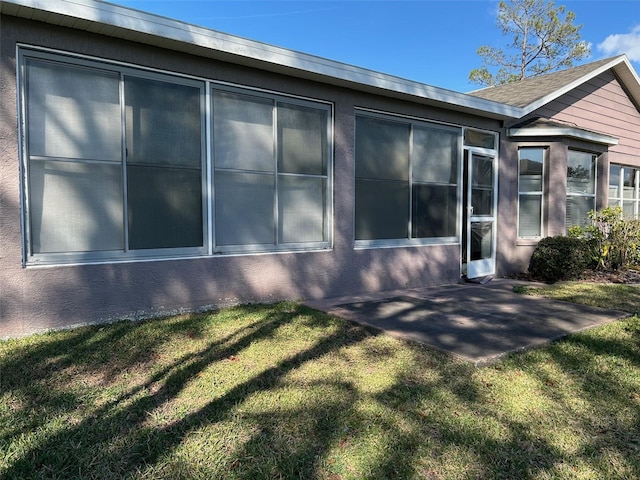 view of side of property featuring a patio area and a lawn