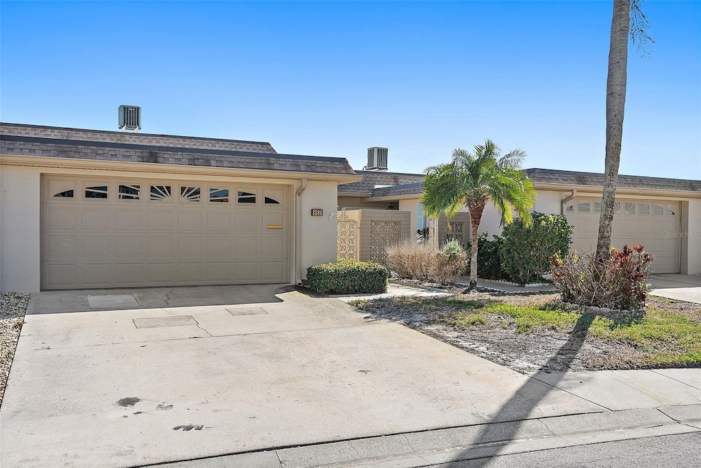 single story home featuring a garage and central AC unit