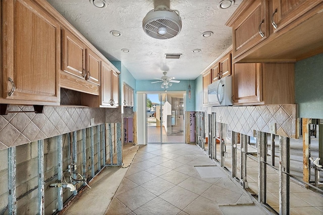 kitchen with ceiling fan, decorative backsplash, light tile patterned floors, and a textured ceiling