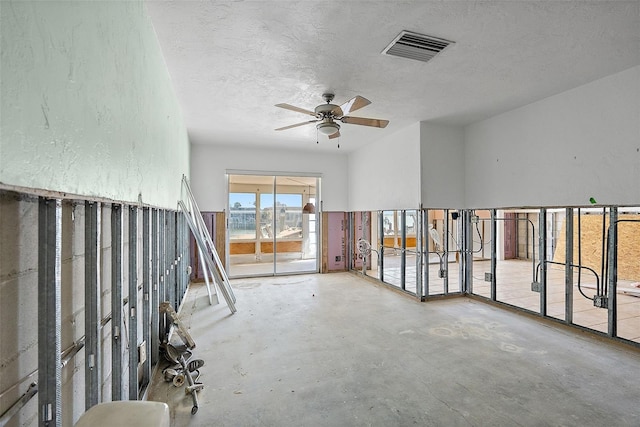 empty room with ceiling fan, concrete flooring, and a textured ceiling