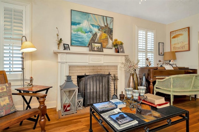 living area with baseboards, a brick fireplace, a wealth of natural light, and light wood-style floors