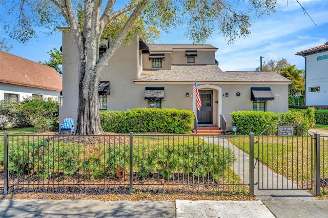 view of front of house with a fenced front yard, a gate, roof with shingles, and stucco siding