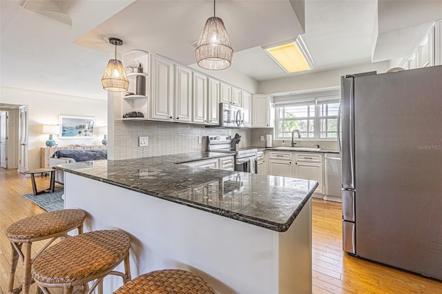 kitchen with white cabinetry, stainless steel appliances, decorative light fixtures, and kitchen peninsula