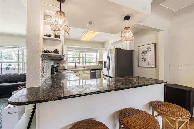 kitchen with a kitchen bar, sink, kitchen peninsula, stainless steel appliances, and white cabinets