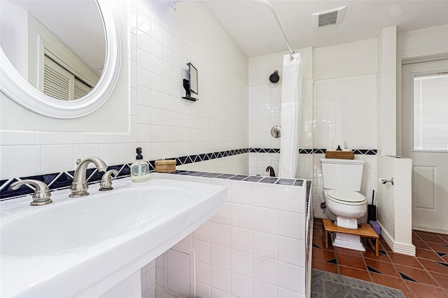 bathroom with sink, tile walls, tile patterned flooring, walk in shower, and toilet