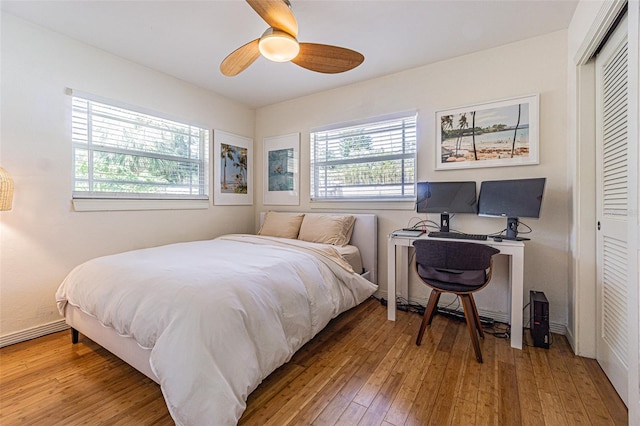 bedroom featuring multiple windows, hardwood / wood-style floors, ceiling fan, and a closet