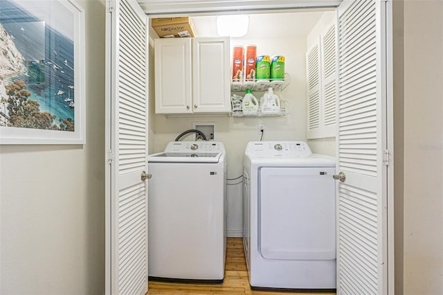 laundry room with cabinets, washing machine and dryer, and light wood-type flooring