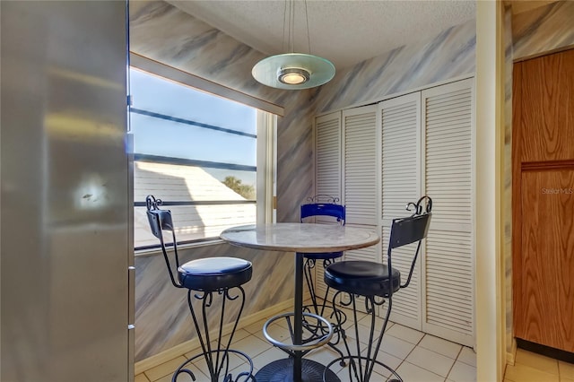 tiled dining area with a textured ceiling