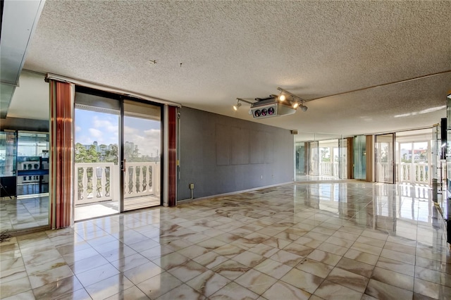 unfurnished room featuring floor to ceiling windows and a textured ceiling