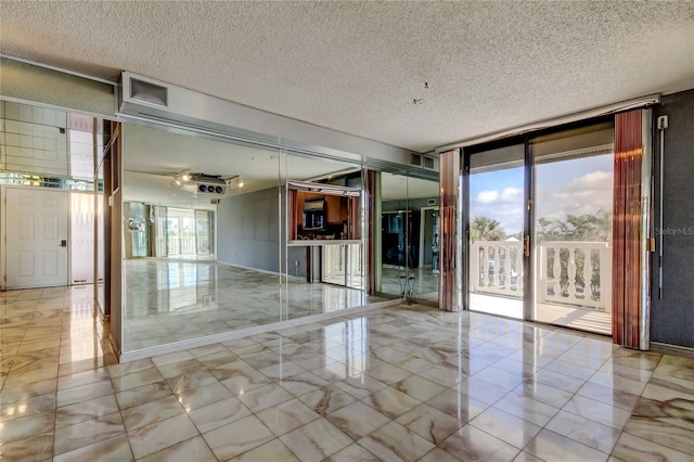 unfurnished room with expansive windows and a textured ceiling