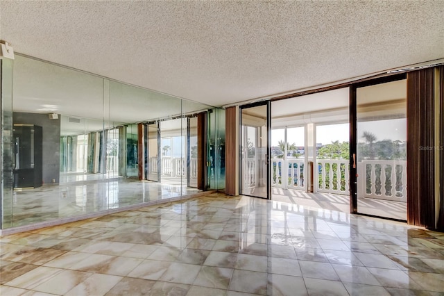 unfurnished room with floor to ceiling windows and a textured ceiling