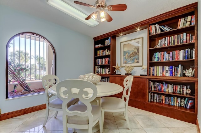 tiled dining area featuring ceiling fan and built in shelves