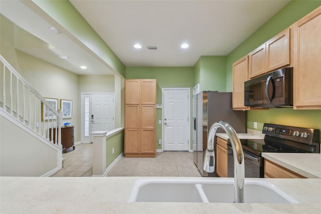 kitchen with light tile patterned flooring, light brown cabinetry, sink, and range with electric stovetop