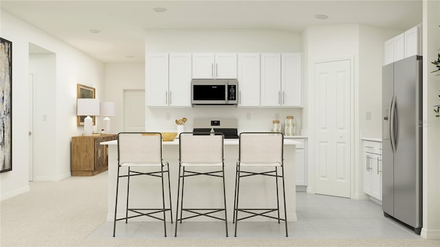 kitchen featuring stainless steel appliances, white cabinetry, a kitchen island, and a kitchen bar